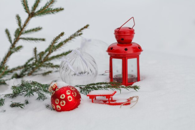 Adorno de Navidad rojo colgado de una rama de pino cubierto de nieve en invierno