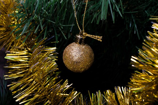 Un adorno navideño dorado colgando de un árbol de navidad