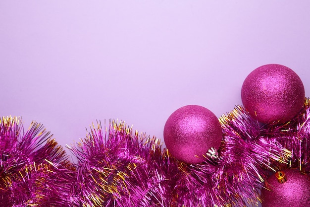 Adornos de bolas de Navidad rosa con oropel sobre fondo púrpura