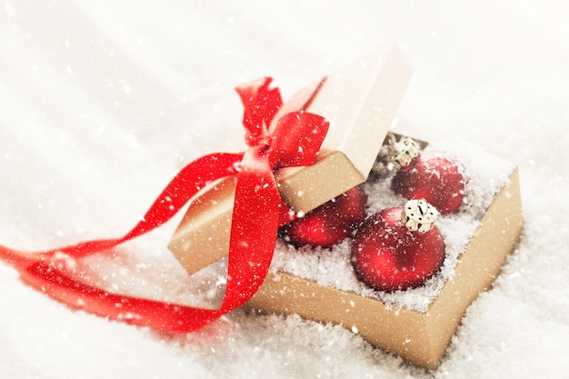 Adornos clásicos rojos hermosos o decoración de Navidad en una caja de regalo con nieve