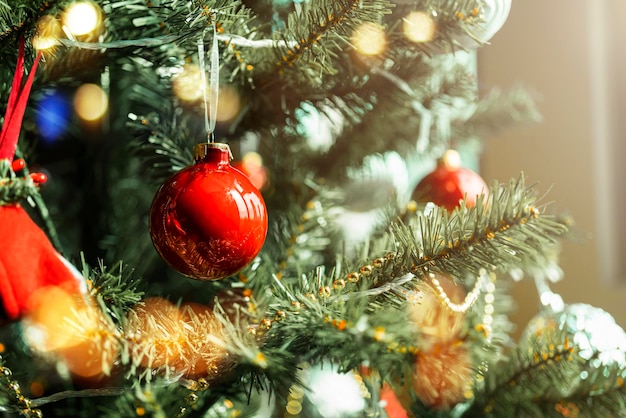 Foto adornos de fondo de navidad y rama de abeto bola roja de navidad brillante colgando de ramas de pino con fondo festivo primer plano de adorno rojo colgando de un árbol de navidad decorado