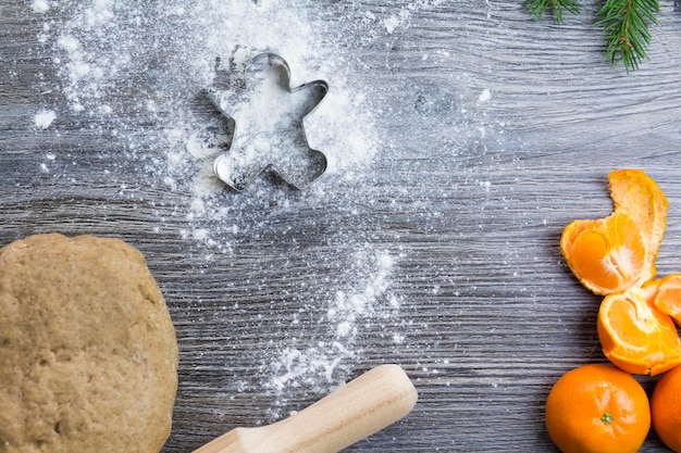 Adornos de Navidad y Año Nuevo en una superficie de madera con mandarinas y un árbol de Navidad Prepare y extienda la masa para hornear pan de jengibre