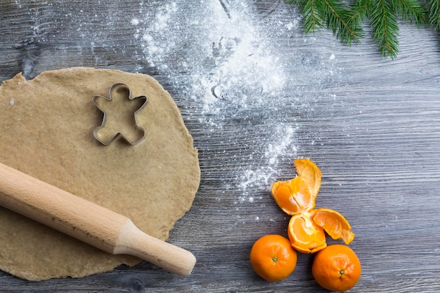 Adornos de Navidad y Año Nuevo en una superficie de madera con mandarinas y un árbol de Navidad Prepare y extienda la masa para hornear pan de jengibre