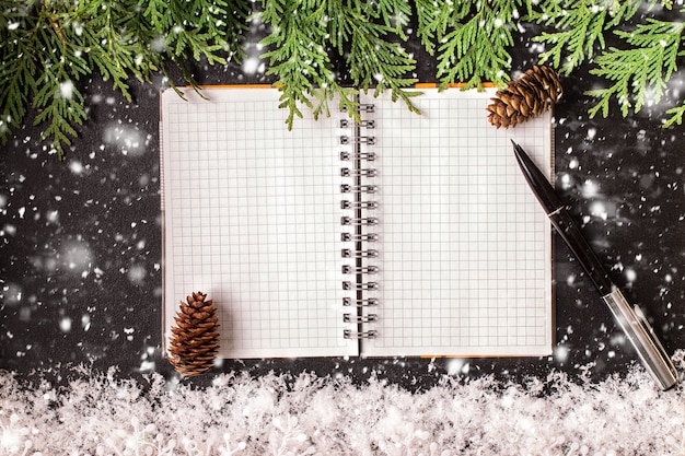 Adornos de Navidad y un cuaderno en blanco abierto en una pizarra