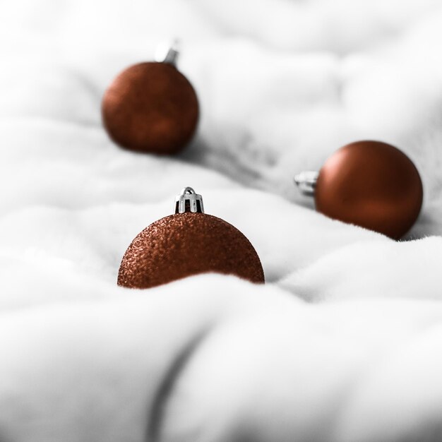 Adornos de Navidad marrón chocolate sobre fondo de piel esponjosa blanca Fondo de diseño de vacaciones de invierno de lujo