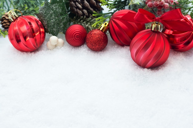 Adornos de Navidad rojo con ramas de abeto, conos de pino, sobre fondo blanco de nieve. Vacaciones de invierno.