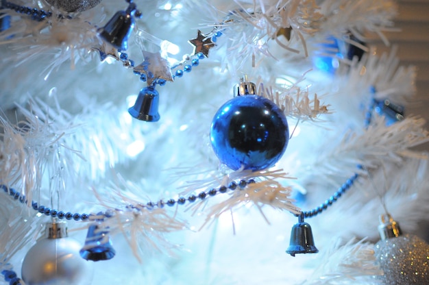 Adornos navideños azules en un árbol de Navidad blanco. De cerca