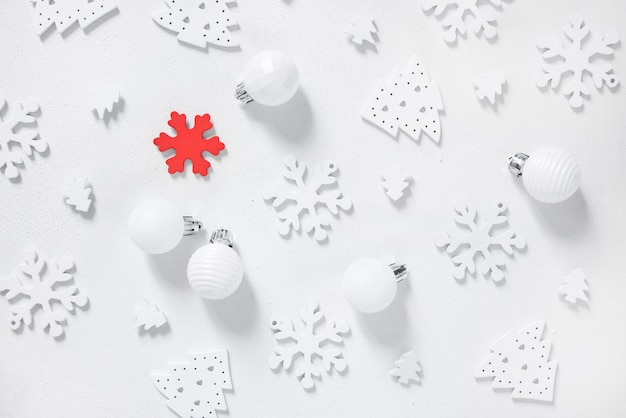 Adornos navideños blancos y rojos y copos de nieve en la vista superior de la mesa blanca. Composición monocromática de invierno con adornos navideños