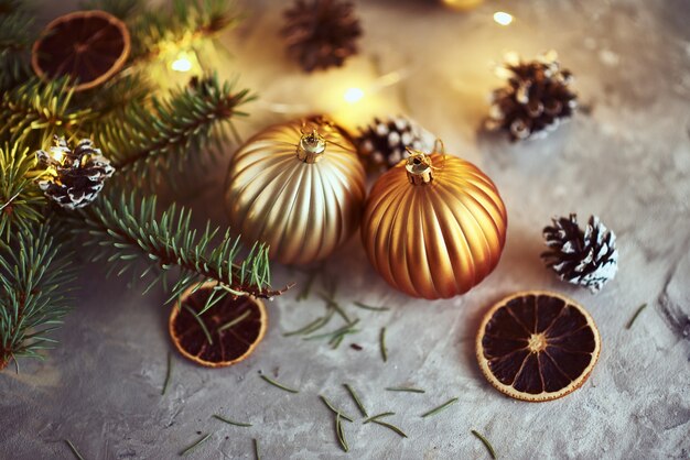 Adornos navideños con bolas doradas, rama de abeto y luces de guirnaldas