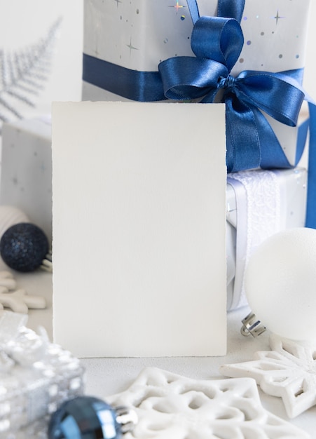 Adornos navideños y caja de regalo con tarjeta en blanco de cerca