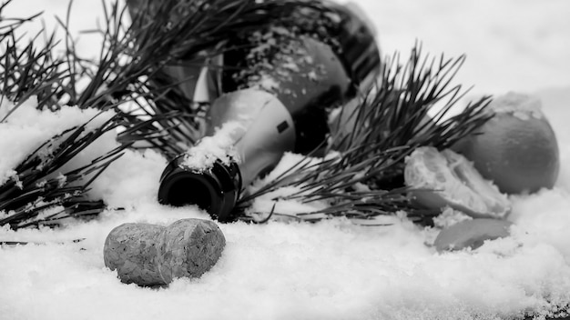 Adornos navideños y champán en la nieve. Decoraciones navideñas en la calle. Estado de ánimo de año nuevo. Velas y globos en el árbol de Navidad.