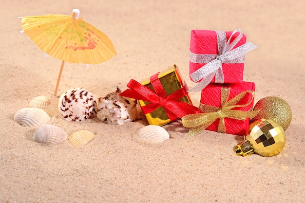 Adornos navideños y conchas en la arena de una playa