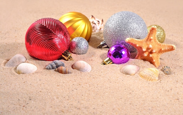 Adornos navideños, conchas y estrellas de mar en la arena de una playa