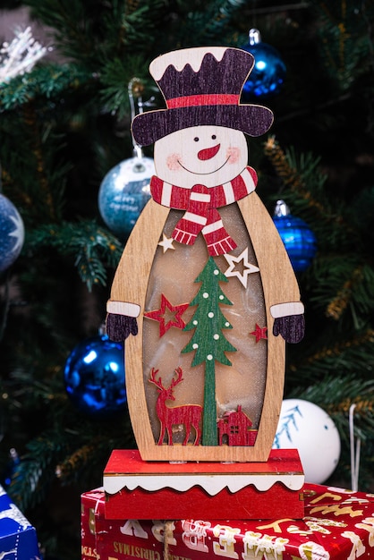 Foto adornos navideños contra el fondo borroso muñeco de nieve de madera pequeño copo de nieve de muñeco de nieve de madera rústica primer plano de muñeco de nieve feliz sonriendo con los brazos arriba tarjeta de felicitación de felices fiestas