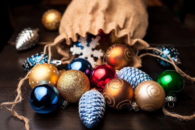 Adornos navideños derramados de una bolsa de lona llena sobre una mesa de madera