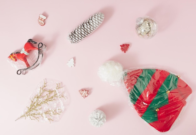 Foto adornos navideños envueltos en lámina de plástico sobre un fondo rosa pálido concepto mínimo