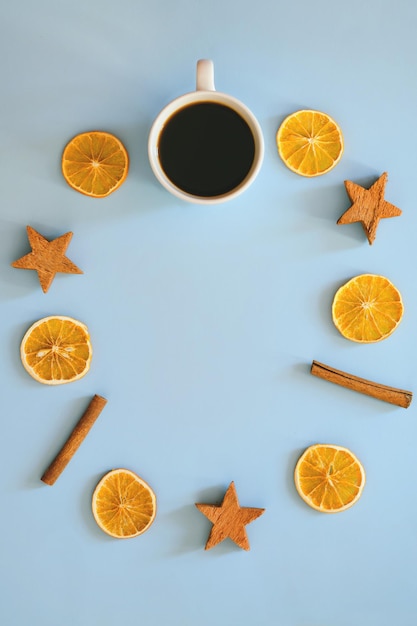 Adornos navideños con especias secas, anillos de naranja y canela. taza de café negro