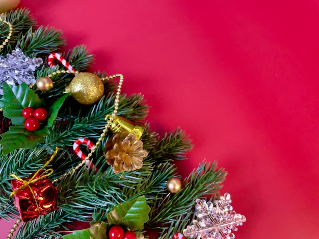 Adornos navideños, hojas de pino, bolas de oro, copos de nieve, frutos rojos sobre fondo rojo.