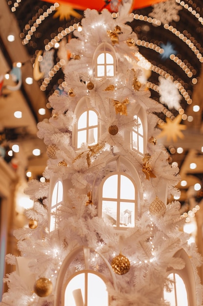 Adornos navideños mágicos en un árbol de Navidad blanco Detalles acogedores con luces doradas bokeh