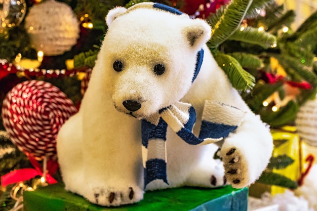 Adornos navideños, un oso polar de juguete se encuentra junto a un árbol de Navidad artificial Exposición estilizada de Nochebuena para los visitantes