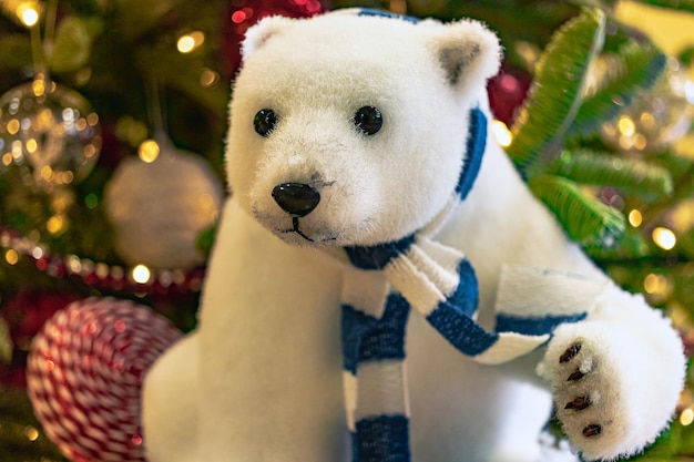 Adornos navideños, un oso polar de juguete se encuentra junto a un árbol de Navidad artificial Exposición estilizada de Nochebuena para los visitantes