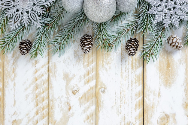 Adornos navideños, piñas y copos de nieve sobre una mesa de madera blanca. Vista superior, copia espacio.