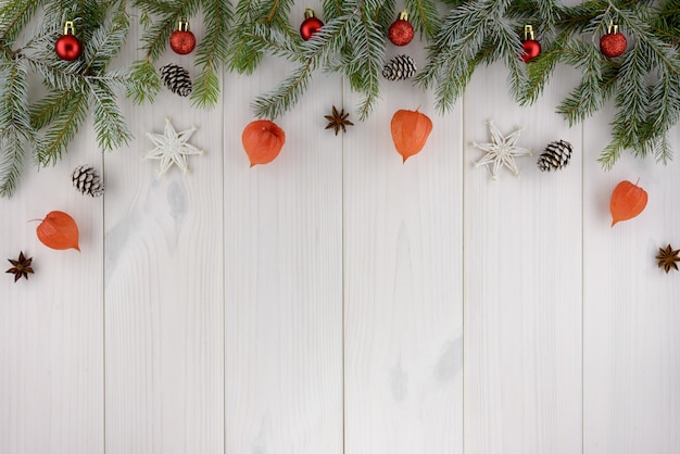 Adornos navideños, piñas, estrellas y bolas rojas sobre una mesa de madera blanca. Vista superior, copia espacio.