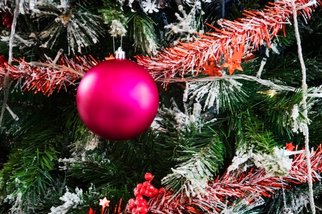 Adornos navideños en pino. Bola de Navidad rosa colgada en el primer plano del árbol de Navidad. ahorra espacio en la bola roja