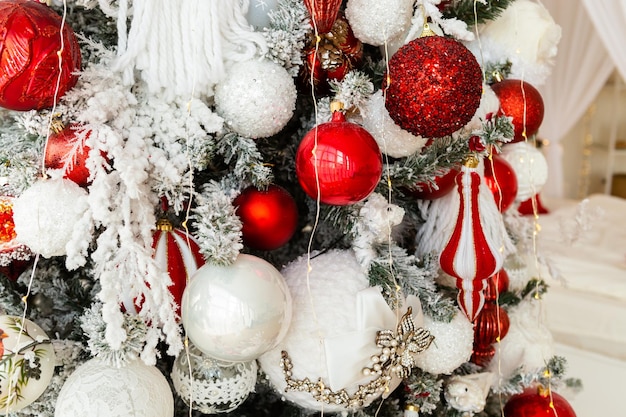 Adornos navideños en un pino colores blanco y rojo Concepto de vacaciones de Navidad y Año Nuevo vista de cerca