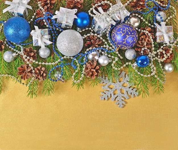 Adornos navideños en una rama de abeto sobre un fondo dorado