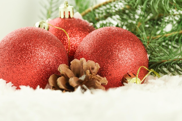 Adornos navideños rojos con un cono de pino y ramas de abeto en el fondo