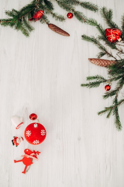 Adornos navideños rojos en una mesa de madera blanca con texto de espacio de copia