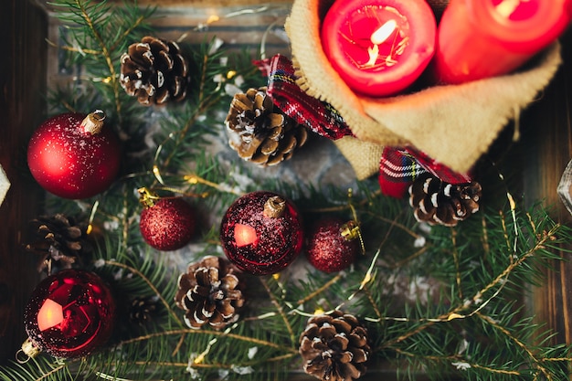 Adornos navideños rojos sobre la mesa en el árbol de Navidad borrosa con velas. Foto de alta calidad