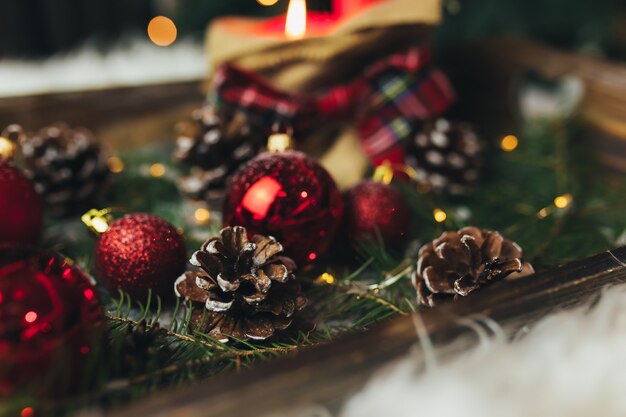 Adornos navideños rojos sobre la mesa en el árbol de Navidad borrosa con velas. Foto de alta calidad