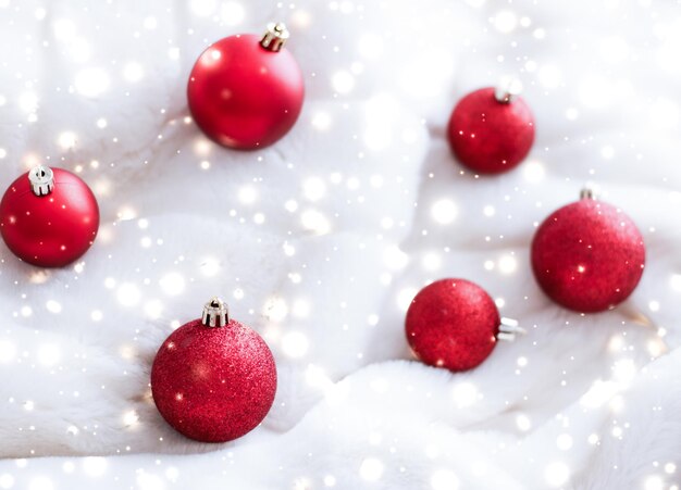 Adornos navideños rojos sobre piel esponjosa con fondo de diseño de vacaciones de invierno de lujo con brillo de nieve