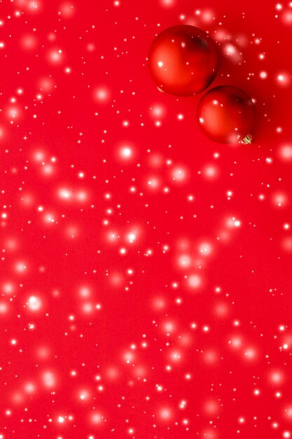Adornos navideños sobre fondo rojo con brillo de nieve tarjeta de vacaciones de invierno de lujo
