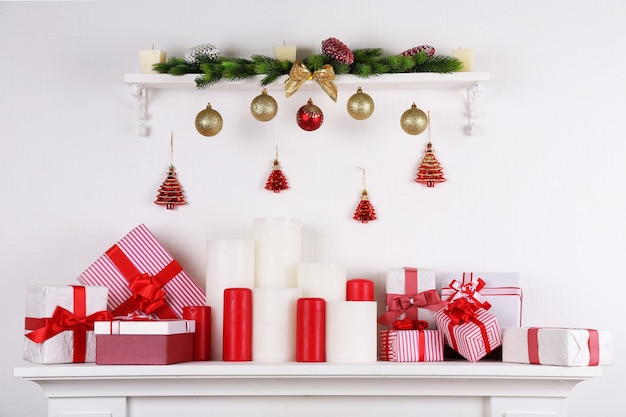 Adornos navideños con velas en la repisa de la chimenea sobre fondo blanco.