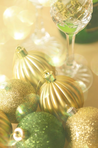 Adornos navideños verdes y dorados sobre un fondo beige composición navideña festiva con una botella de champán y copas con enfoque selectivo