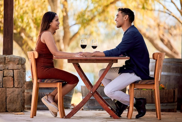 Adoro a sensação de me arrumar para sair com meu amor Foto de um jovem casal tomando vinho em um encontro em uma fazenda de vinhos