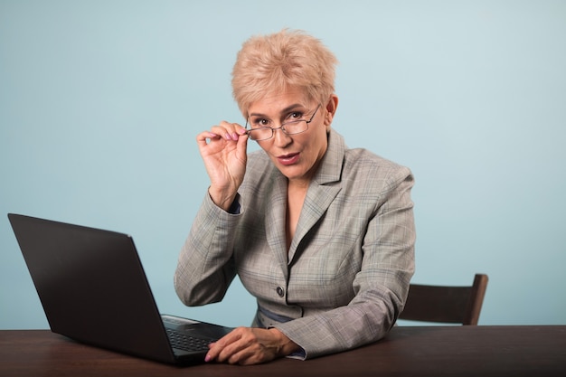 adulta elegante mulher atraente com corte de cabelo curto em um terno à mesa com um laptop