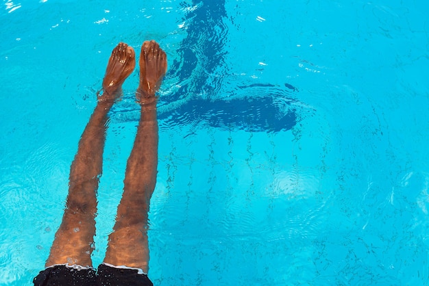Adulto afro-americano com as pernas embaixo d'água na piscina