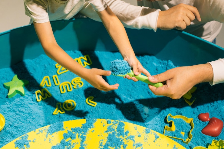 Foto el adulto ayuda al niño en el juego con arena cinética. terapia artística. aliviar el estrés y la tensión. sensaciones táctiles. creatividad y placer. desarrollo de la motricidad fina. concentración y atención.