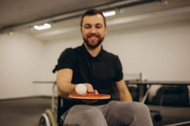 Un adulto discapacitado en silla de ruedas juega tenis de mesa Un juego de ping pong