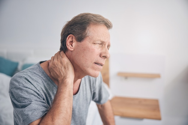 Adulto do sexo masculino franzindo a testa enquanto se sente mal após a atividade física, estando em casa