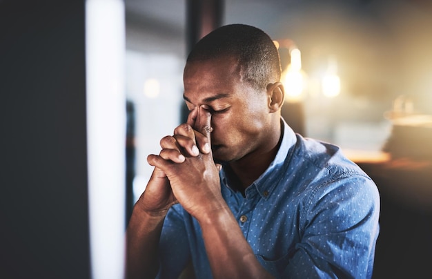 Adulto é difícil tiro recortado de um jovem empresário bonito experimentando estresse durante a noite no trabalho