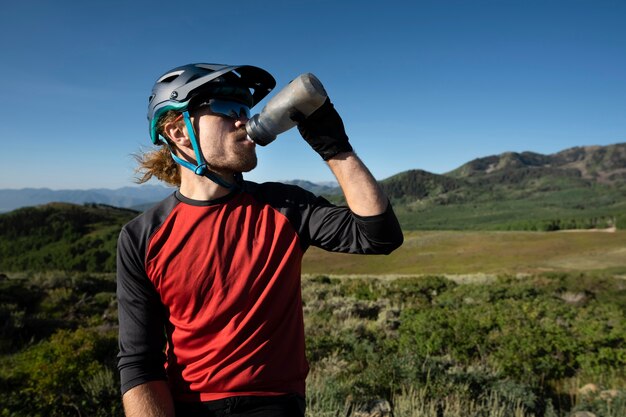 Adulto joven con bicicleta eléctrica en el campo