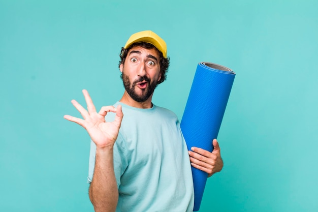 Adulto joven hispano loco con un matt de yoga