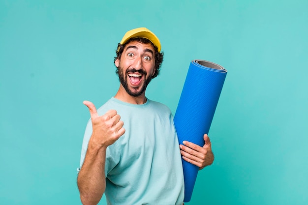 Adulto joven hispano loco con un matt de yoga