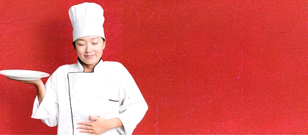 Adulto joven mujer bastante asiática chef de restaurante sosteniendo un plato vacío