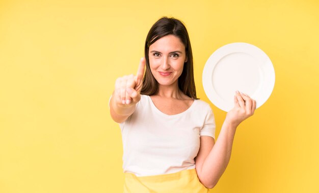 Adulto joven mujer bonita chef casero con plato vacío